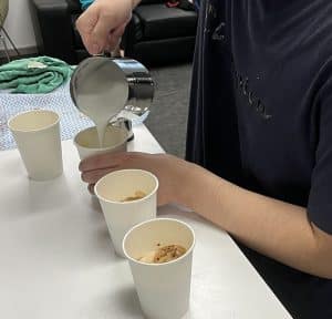 Hospitality student pouring steamed milk into coffee cups during barista training at VTS