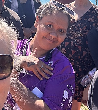 Smiling student at an outdoor celebration wearing a purple jersey, recognised as Regional Student of the Month